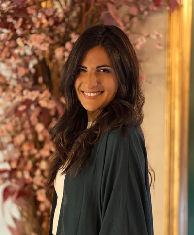 Samantha Sacchi smiling beside a flowering wall